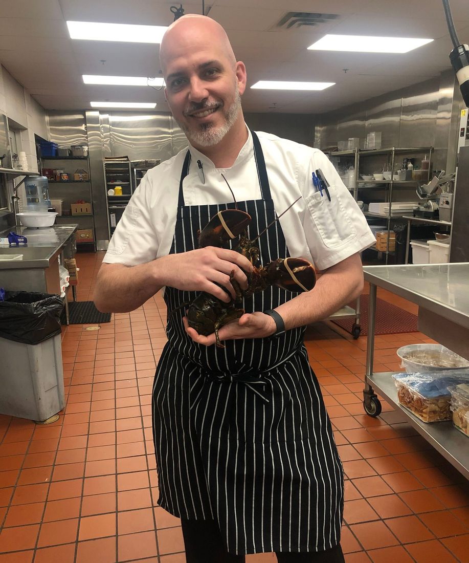 Chef Jackson Locklear holding a live lobster in a restaurant kitchen