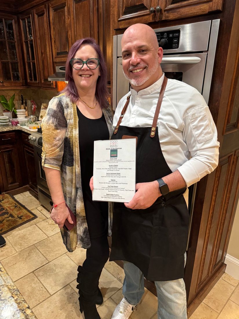 Private chef Jackson Locklear with a dinner guest holding the Dinner of the Americas menu