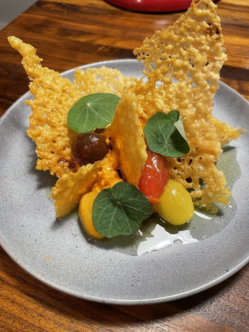 Parmesan crisp pizza with nduja espuma and heirloom cherry tomatoes, plated by private chef Jackson Locklear