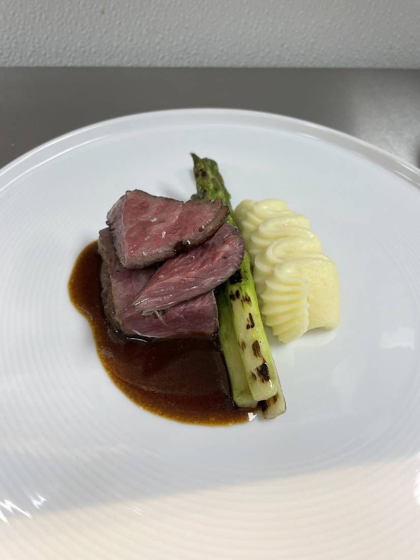 Steak with demi sauce, charred asparagus, and pommes purée, plated by private chef Jackson Locklear