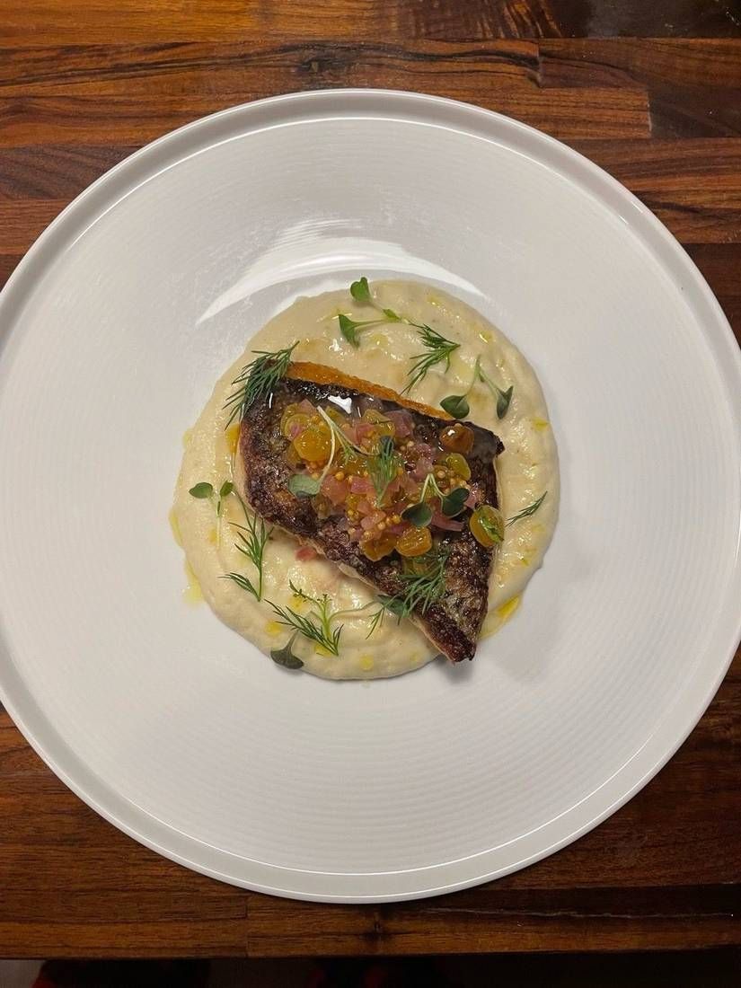 Striped bass with celeriac purée and golden raisin agrodolce, plated by private chef Jackson Locklear